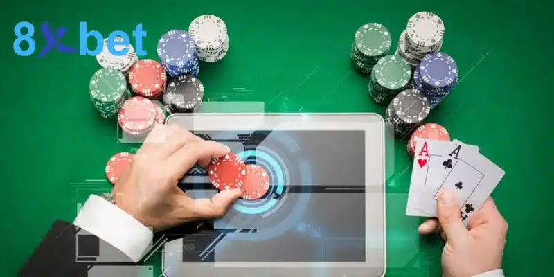 Tay người chơi đặt chip trên máy tính bảng khi chơi casino online, bên cạnh cặp bài A