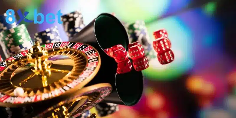 Vòng quay roulette, cốc lắc và xúc xắc đỏ bên các chồng chip, tượng trưng cho sảnh casino online 8xbet