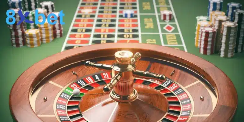 Bàn đặt cược roulette nỉ xanh với bánh xe, quả bóng trắng và các chồng chip hai bên