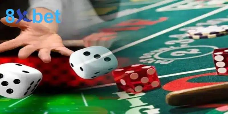 Bàn tay tung xúc xắc trắng và đỏ trên bàn Sic Bo, gợi nhắc bảng trả thưởng trong luật chơi tài xỉu