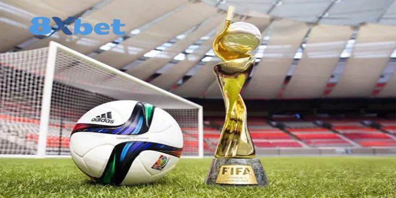 Quả bóng và cúp vàng FIFA đặt trên sân cỏ cạnh khung thành, gợi không khí mùa kèo world cup