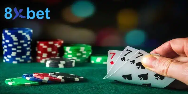 Tay lật ba lá 7 trên bàn nỉ xanh cạnh các chồng chip, bộ sáp 7 hiếm gặp trong bài cào 3 lá