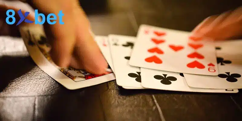 Người chơi bài phỏm online lật các lá bài chuồn và cơ trên mặt bàn gỗ tối màu