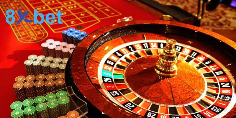 Cận cảnh bánh xe dùng để đặt cược roulette bên bàn nỉ đỏ và nhiều chồng chip màu