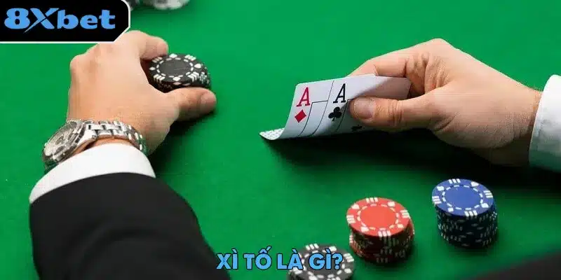 Người chơi xì tố hé xem đôi A dưới tay, bên cạnh các chồng chip đỏ và xanh trên bàn nỉ xanh