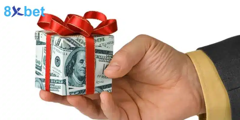 Bàn tay cầm hộp quà gói bằng tiền giấy thắt nơ đỏ, tượng trưng giải thưởng keno minh chính
