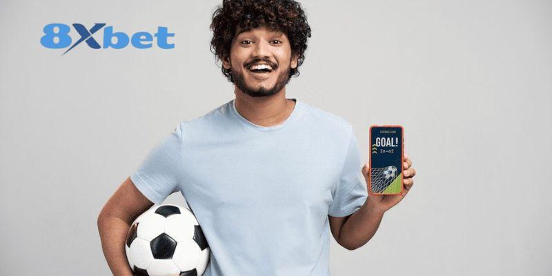 Chàng trai ôm quả bóng và cầm điện thoại hiện chữ GOAL, minh họa theo dõi soi kèo world cup trên di động